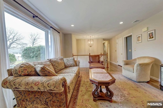 living room with a baseboard radiator, a notable chandelier, and light hardwood / wood-style flooring