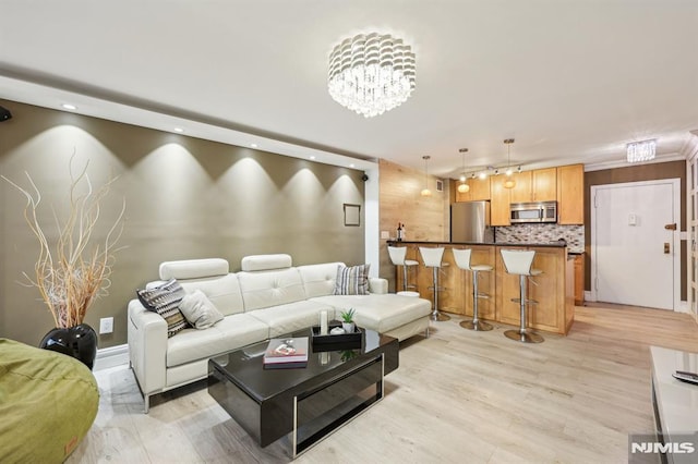 living room with light hardwood / wood-style floors and a notable chandelier