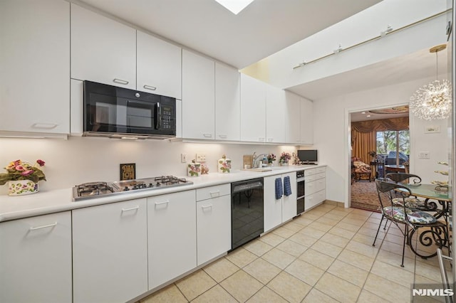 kitchen featuring light tile patterned flooring, pendant lighting, white cabinets, and black appliances