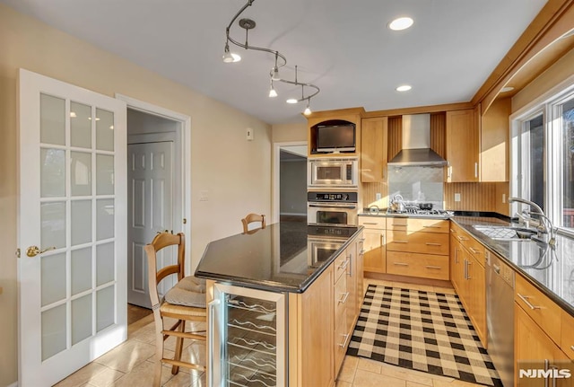 kitchen with stainless steel appliances, wall chimney range hood, light brown cabinets, wine cooler, and sink