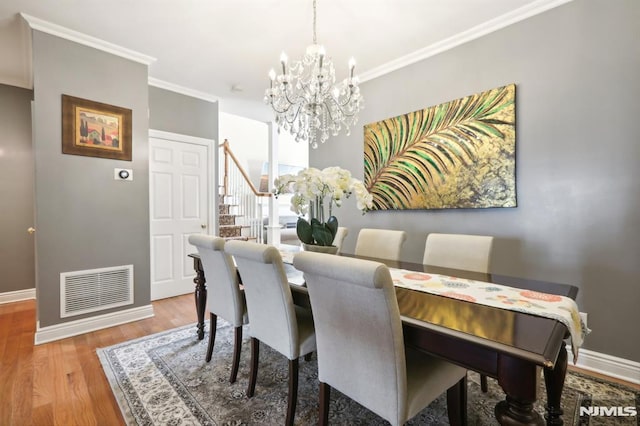 dining space featuring hardwood / wood-style floors, an inviting chandelier, and crown molding