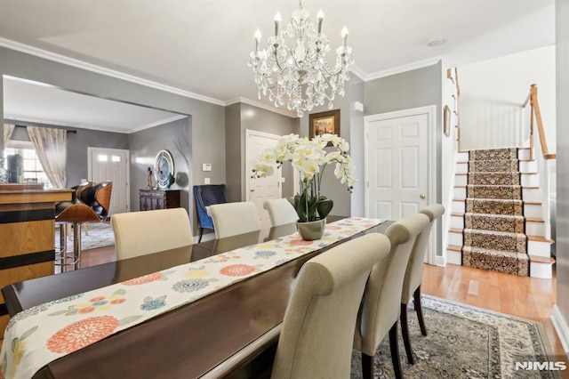 dining space featuring hardwood / wood-style flooring, an inviting chandelier, and crown molding