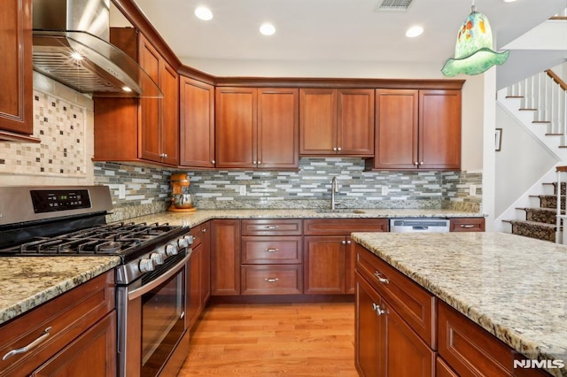 kitchen with sink, wall chimney range hood, tasteful backsplash, and appliances with stainless steel finishes