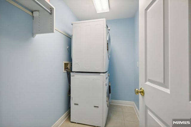 laundry area with light tile patterned flooring and stacked washer / dryer