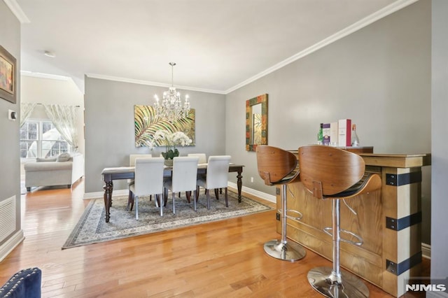 dining area with a notable chandelier, crown molding, and light hardwood / wood-style flooring