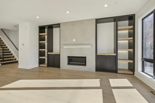 unfurnished living room featuring hardwood / wood-style floors and built in shelves