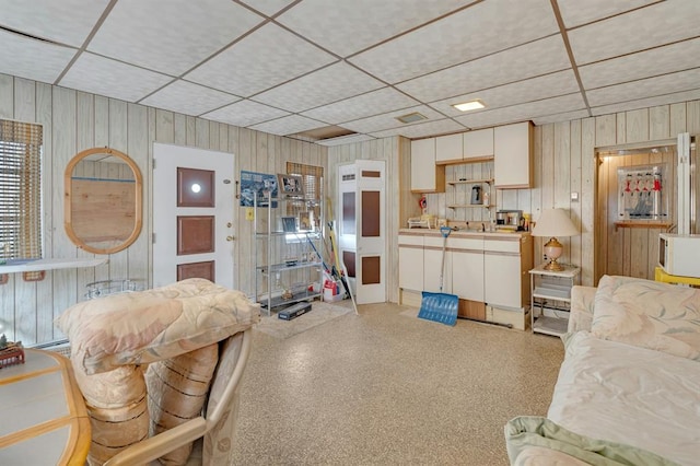 living room featuring wood walls and a drop ceiling