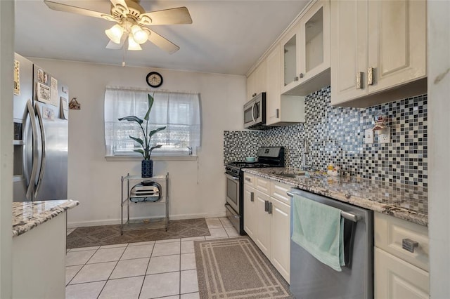 kitchen with light stone countertops, tasteful backsplash, stainless steel appliances, light tile patterned floors, and white cabinets