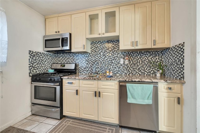 kitchen with backsplash, sink, light stone countertops, and stainless steel appliances