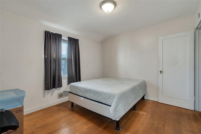 bedroom with wood-type flooring and lofted ceiling