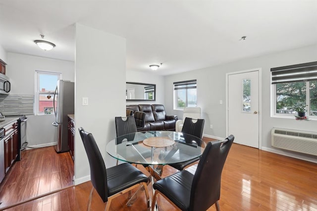 dining area featuring a wall unit AC and hardwood / wood-style flooring