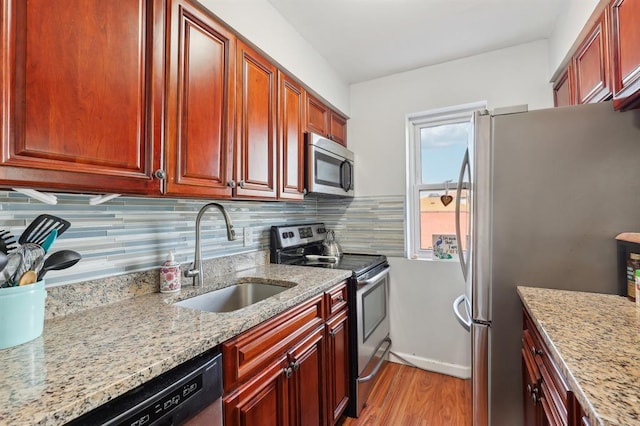 kitchen featuring light stone counters, sink, stainless steel appliances, and tasteful backsplash