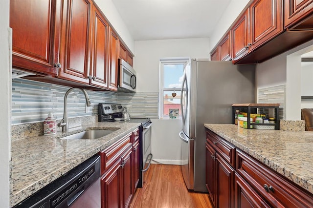 kitchen featuring backsplash, light stone counters, sink, and appliances with stainless steel finishes