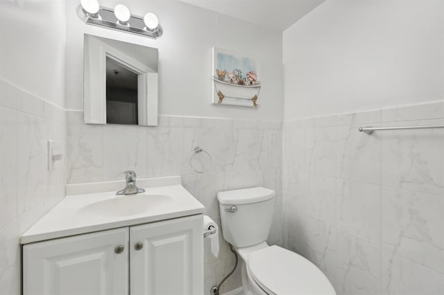 bathroom featuring vanity, toilet, and tile walls