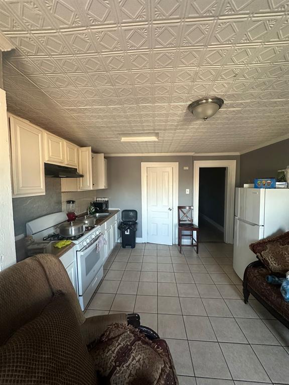 kitchen featuring light tile patterned floors, white appliances, a textured ceiling, and white cabinetry