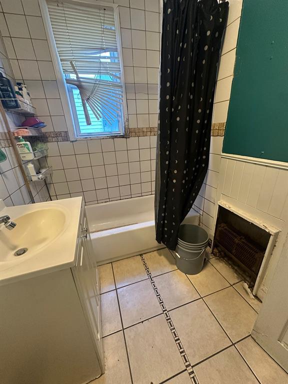 bathroom with vanity, tile patterned flooring, shower / bathtub combination with curtain, a fireplace, and tile walls