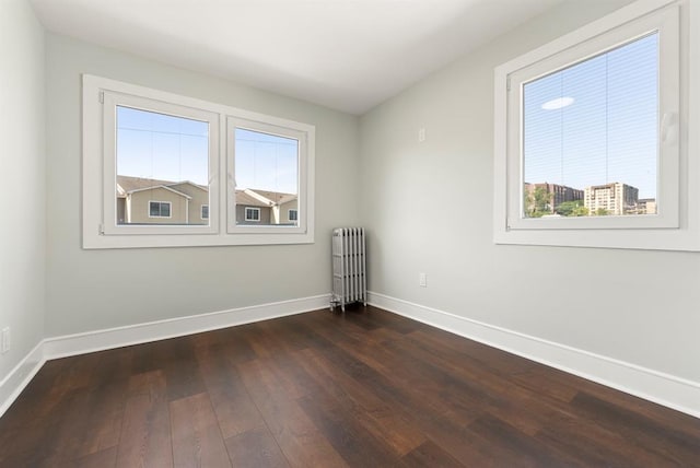 unfurnished room with dark hardwood / wood-style flooring and radiator