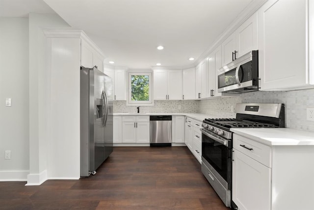 kitchen featuring dark wood-type flooring, white cabinets, sink, appliances with stainless steel finishes, and tasteful backsplash