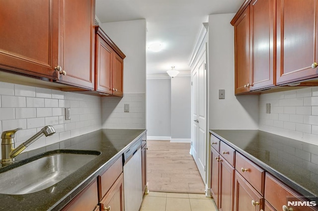 kitchen with backsplash, dark stone counters, sink, dishwasher, and light tile patterned flooring