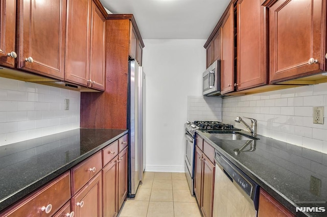 kitchen with dark stone countertops, light tile patterned floors, stainless steel appliances, and tasteful backsplash