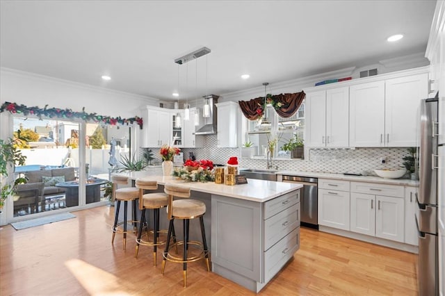 kitchen featuring white cabinetry, sink, decorative light fixtures, a kitchen island, and appliances with stainless steel finishes