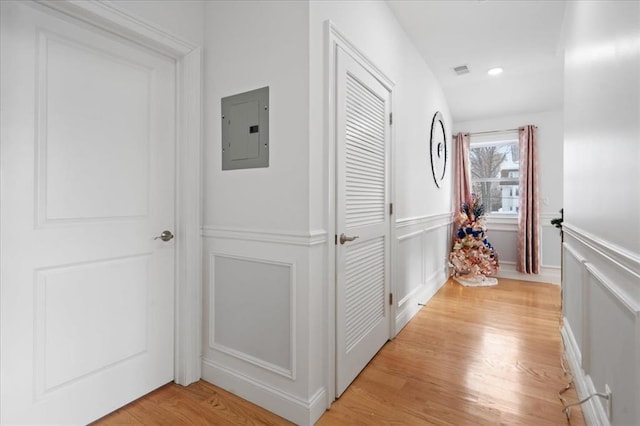 corridor featuring electric panel and light hardwood / wood-style flooring