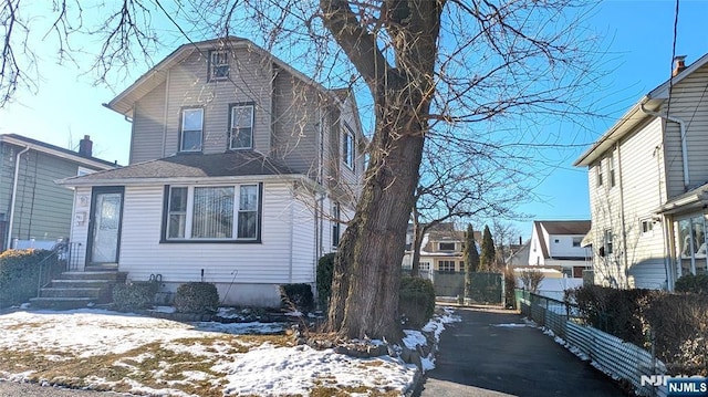 view of front of home with fence, driveway, and roof with shingles