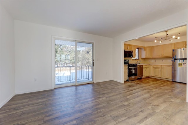 kitchen featuring sink, light brown cabinets, stainless steel appliances, an inviting chandelier, and wood-type flooring