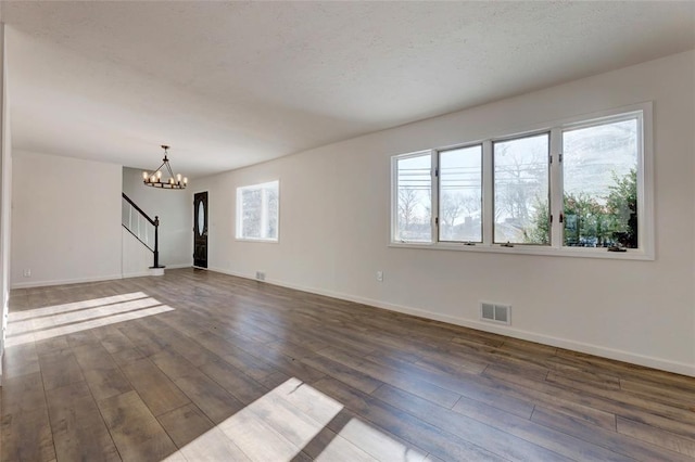 spare room with dark wood-type flooring and an inviting chandelier