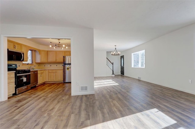 kitchen with appliances with stainless steel finishes, light brown cabinets, a chandelier, light hardwood / wood-style floors, and hanging light fixtures