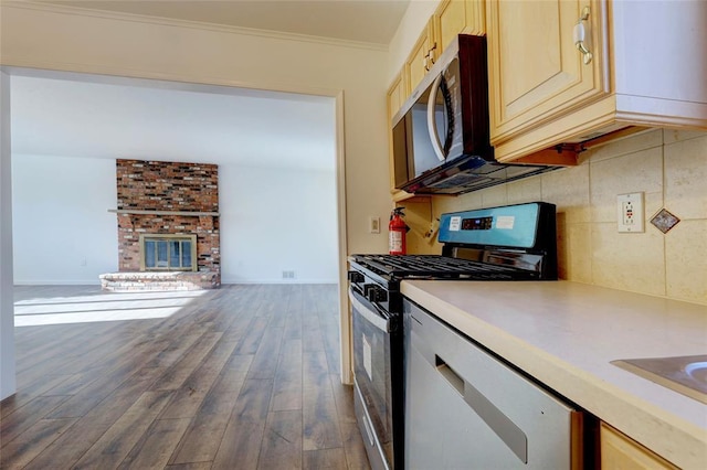 kitchen with gas range, crown molding, light brown cabinetry, and a fireplace