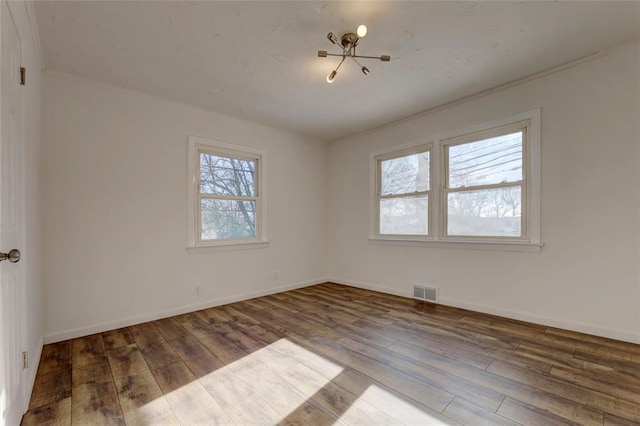 unfurnished room with hardwood / wood-style flooring and an inviting chandelier