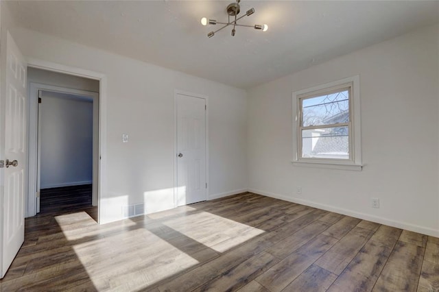 unfurnished bedroom featuring a closet, dark hardwood / wood-style flooring, and a notable chandelier