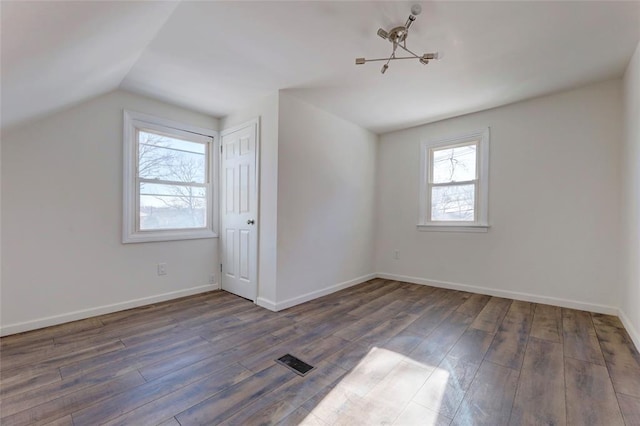 bonus room with dark wood-type flooring, lofted ceiling, and a notable chandelier