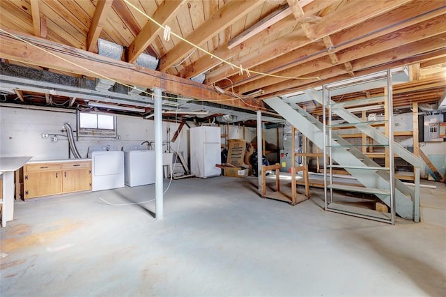 basement featuring washing machine and dryer, electric panel, and white refrigerator