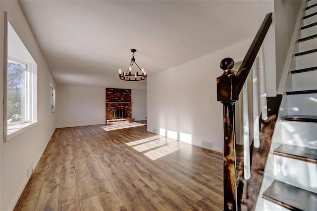 unfurnished living room with a fireplace, wood-type flooring, and a notable chandelier