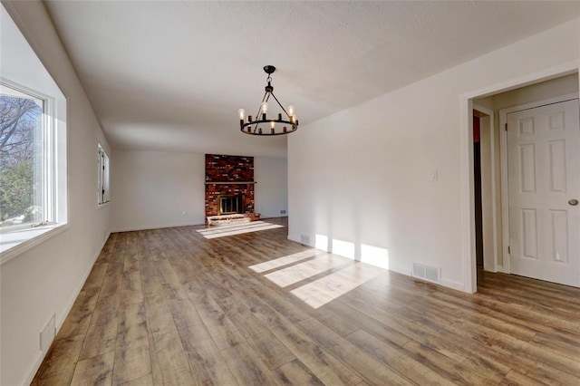 interior space with hardwood / wood-style flooring, a chandelier, and a brick fireplace