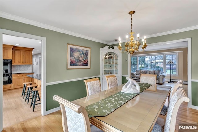 dining area with crown molding, light hardwood / wood-style flooring, and a notable chandelier