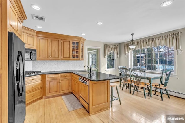 kitchen featuring black appliances, a kitchen breakfast bar, sink, decorative light fixtures, and kitchen peninsula