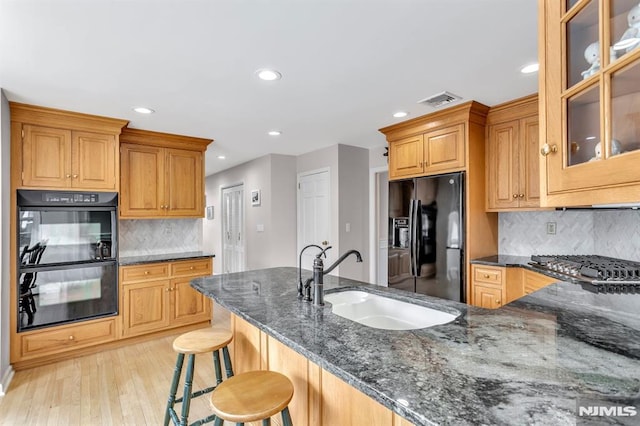 kitchen with backsplash, dark stone countertops, sink, and black appliances