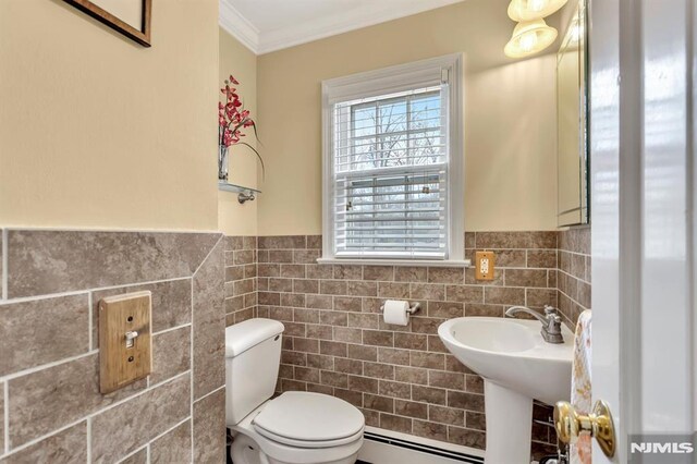 bathroom featuring toilet, ornamental molding, tile walls, and a baseboard heating unit