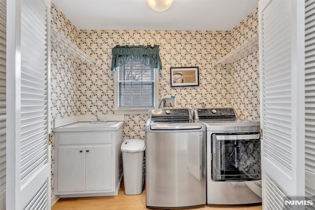 washroom with sink, washer and dryer, and light hardwood / wood-style floors