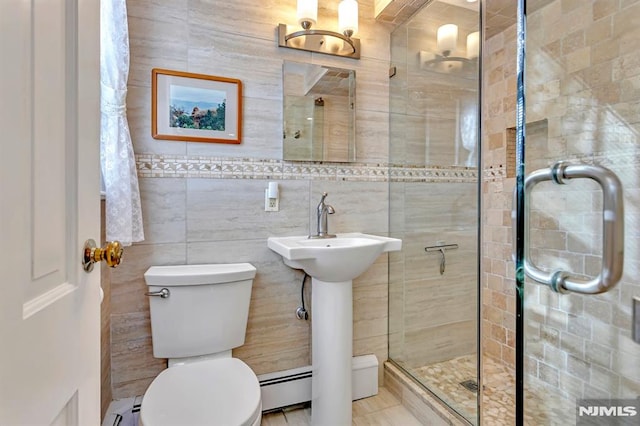 bathroom with toilet, a shower with door, tile walls, and a baseboard heating unit