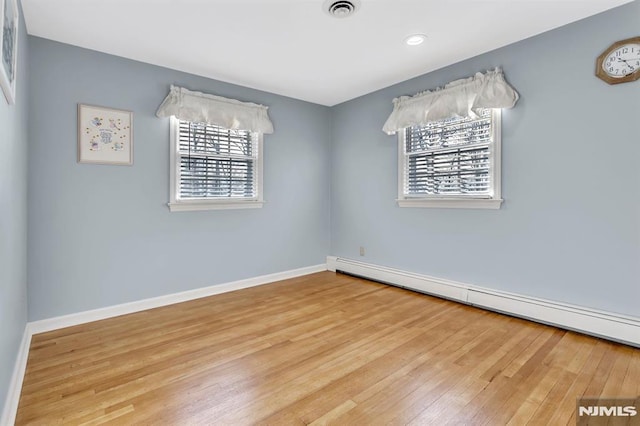 spare room featuring hardwood / wood-style floors and a baseboard heating unit