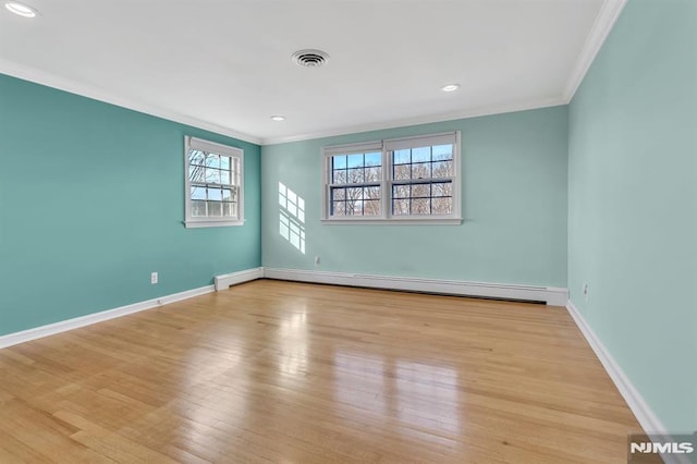 spare room with ornamental molding, baseboard heating, and light hardwood / wood-style flooring