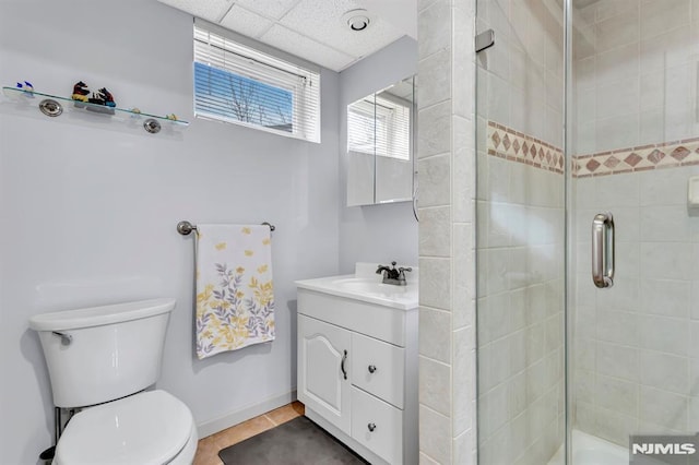 bathroom featuring a paneled ceiling, tile patterned floors, vanity, toilet, and a shower with shower door