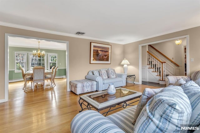 living room with crown molding, light hardwood / wood-style floors, a baseboard heating unit, and a notable chandelier