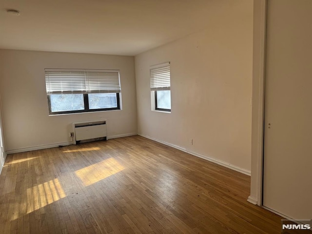 empty room with hardwood / wood-style flooring and radiator