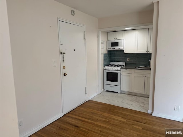 kitchen featuring white appliances, white cabinetry, tasteful backsplash, and light hardwood / wood-style flooring