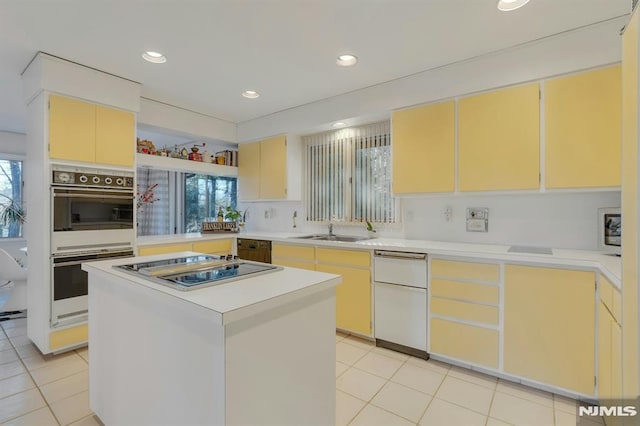 kitchen with white double oven, a healthy amount of sunlight, sink, and a kitchen island